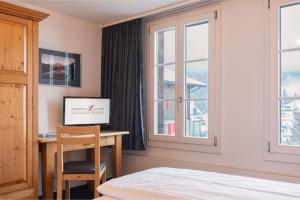 格林德尔瓦尔德瑞士山圣母峰洛奇酒店的一间卧室配有书桌、一张床和窗户。