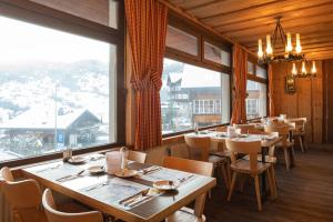 格林德尔瓦尔德瑞士山圣母峰洛奇酒店的餐厅设有桌椅和大窗户。