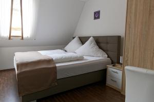 沃尔姆斯Hotel Hüttl - Garni的一张带白色床单和枕头的床