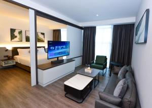 古晋Rume Hotel的酒店客房配有床、沙发和电视。