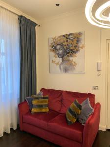 锡比乌Schillerplatz Apartment的客厅里一张红色的沙发,上面有绘画作品