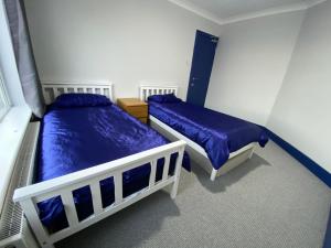 金斯林Harewood Lodge - Single and Double Rooms Self Serve Apartment的卧室设有两张床铺,配有蓝色床单