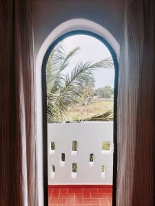 斯基灵角Maison d'hôtes Keur Racine的棕榈树客房内的拱形窗户
