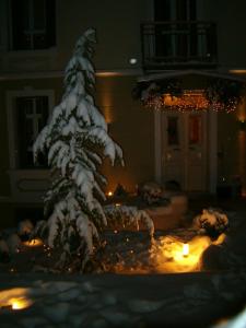 卡斯托里亚Room in Faneromeni's grove的雪覆盖的圣诞树,在院子里放着蜡烛