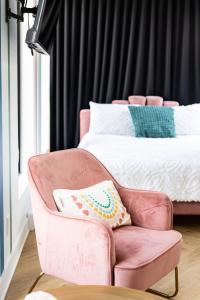 泰勒博恩Le Virtuose - Vieux-Terrebonne的粉红色的椅子、枕头和床