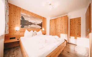 斯拉德明Posers Bergwelt的一张白色大床,位于带木墙的房间
