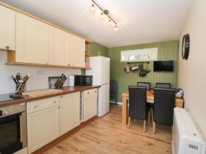 马姆斯伯里Orchard House Cottage的厨房配有白色橱柜和桌椅