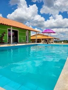 卡兰卡斯Pousada Sal da Terra的一个带房子和紫色遮阳伞的游泳池