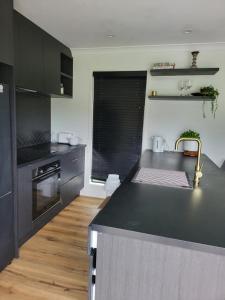 陶朗加Kotuku Cottage的厨房配有黑色台面和水槽