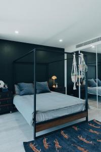 悉尼‘The Lumos’ Designer home Close to Olympic Park的一间卧室设有天蓬床和黑色墙壁