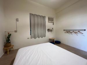 小琉球岛暖流背包客栈的卧室配有白色的床和窗户。