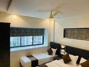 孟买HOTEL BLACK BURN的客房设有两张床和窗户。