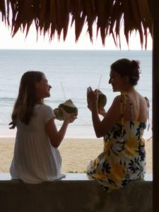 奈通海滩Sealord Naithon Beachfront Villa的两名坐在海滩上喝饮料的女人