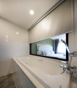 清迈Prime Square Hotel的一间带浴缸和大镜子的浴室