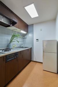 东京Holiday Places /SHIBUYA 5min by train (Sangenjaya)的厨房配有棕色橱柜和白色冰箱