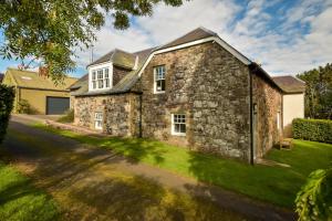 DunningThe Steading at Pitmeadow Farm的一座古老的石头房子,设有绿色草坪