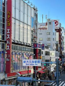 东京Shinokubo guest house的一条繁忙的城市街道,有高大的建筑和标志