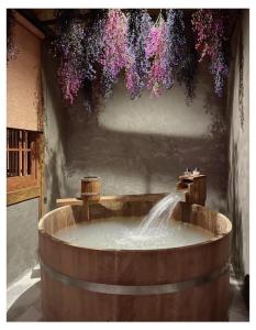 曼谷MAYU Bangkok Japanese Style Hotel的木浴缸,喷泉上挂着鲜花