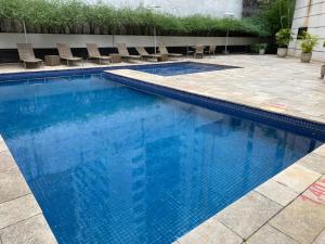 圣保罗Flat Jardins, entre Av Paulista e Parque do Ibiraquera的一个带蓝色水和椅子的游泳池