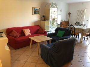 科雷多Appartamento Rosa的客厅配有红色的沙发、椅子和桌子