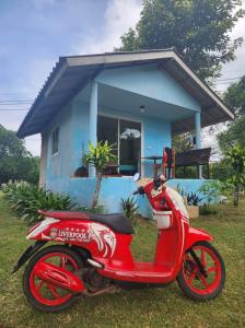 麦岛Miss You Beach Resort Koh Mak的停在蓝色房子前面的一辆红色摩托车