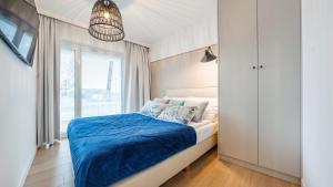 科沃布热格Apartament Lux Tukan B002, Polanki Aqua - Holiday City的一间卧室配有一张带蓝色床单的床和一扇窗户。