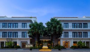 暹粒库伦酒店的一座白色的建筑,前面有棕榈树