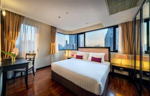 曼谷Bandara Silom Suites, Bangkok的酒店客房设有一张床、一张书桌和窗户。
