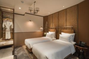 河内La Passion Hanoi Hotel & Spa的酒店客房设有两张床和一个衣柜。