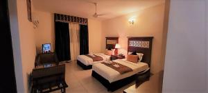 吉布提Ras Dika Hotel的酒店客房设有两张床和电视。