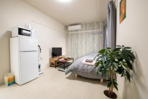 东京ミニマリズムホテル葛飾的小房间设有一张床和一台冰箱