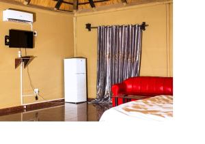 奥奇瓦龙戈MSC Hotel Otjiwarongo的一间设有床铺、红色沙发和电视的房间