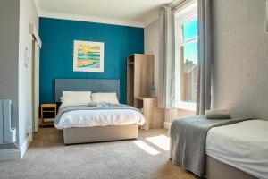 克罗默三德克里夫旅馆的一间卧室设有两张床和蓝色的墙壁