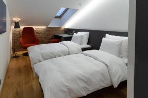 塔林Dunten Hotel的客房设有2张带白色床单和椅子的床。