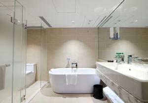 香港香港金域假日酒店的浴室配有2个盥洗盆、浴缸和淋浴。