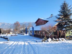 SúľovPenzión Štefánik的雪地中的一座建筑,有圣诞树