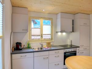 因特拉肯Holiday Home Chalet Dori by Interhome的厨房配有白色橱柜、水槽和桌子