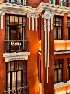 伊斯坦布尔RUZ Hotels的橙色的建筑,设有阳台和桌子