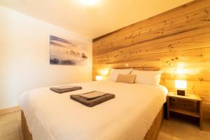 梅杰夫Cozzy appart dans chalet vue Mont-Blanc 2 chambres的卧室配有一张白色大床和木墙