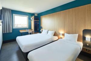 舍维伊拉吕B&B HOTEL Orly Chevilly-Larue - Nationale 7的两张位于酒店客房的床,拥有蓝色的墙壁