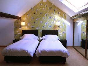 于伊费尔梅阿西恩酒店的一间卧室配有两张带白色床单和墙壁的床。