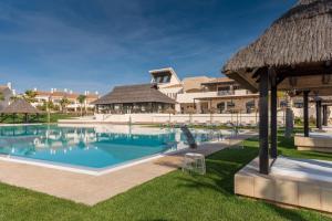 弗安特阿拉莫Ona Hacienda del Álamo Golf Resort的一座带茅草屋顶的度假村内的大型游泳池