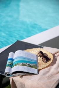 拉奥利瓦Villa Casilla de Costa Private Pool Luxury La Oliva By Holidays Home的坐在游泳池旁的桌子上看书和太阳镜