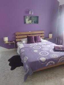 明德卢Maderalzinho的一间卧室配有一张紫色墙壁的床