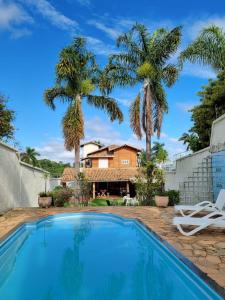 贝洛奥里藏特Woods Hostel的一座带游泳池和棕榈树的房子