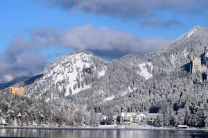 施万高AMERON Neuschwanstein Alpsee Resort & Spa的山地,在湖旁被雪覆盖