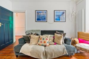伦敦Stunning one bedroom flat with large terrace in Chiswick by UnderTheDoormat的客厅配有带枕头的沙发
