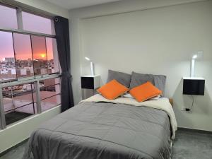 特鲁希略Apartamentos "APPART D'ELIETTE"的一间卧室配有带橙色枕头的床和窗户。