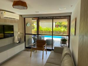 嘎林海斯港Muro alto Bangalô beach class ecolife的带沙发的客厅,享有游泳池的景色