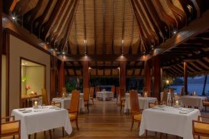 马埃岛Anantara Maia Seychelles Villas的一间设有白色桌椅的用餐室